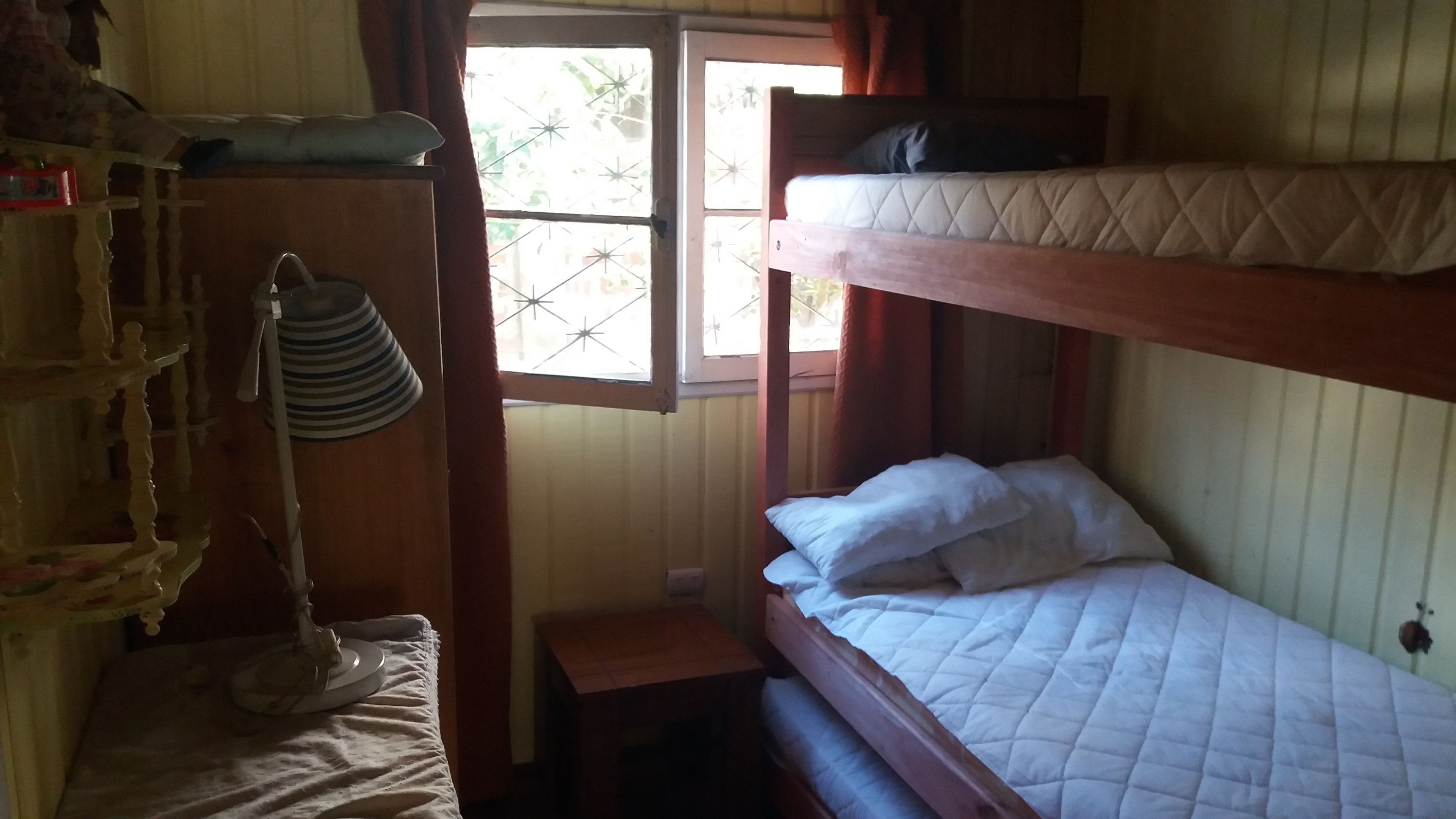 A dormitory room with bunk beds, a small table, and a hanging lamp.