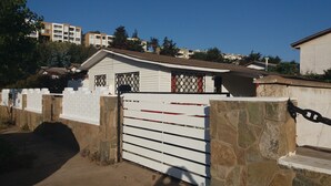 Un lotissement résidentiel fermé, avec une maison blanche, des murs en pierre et un portail en métal.