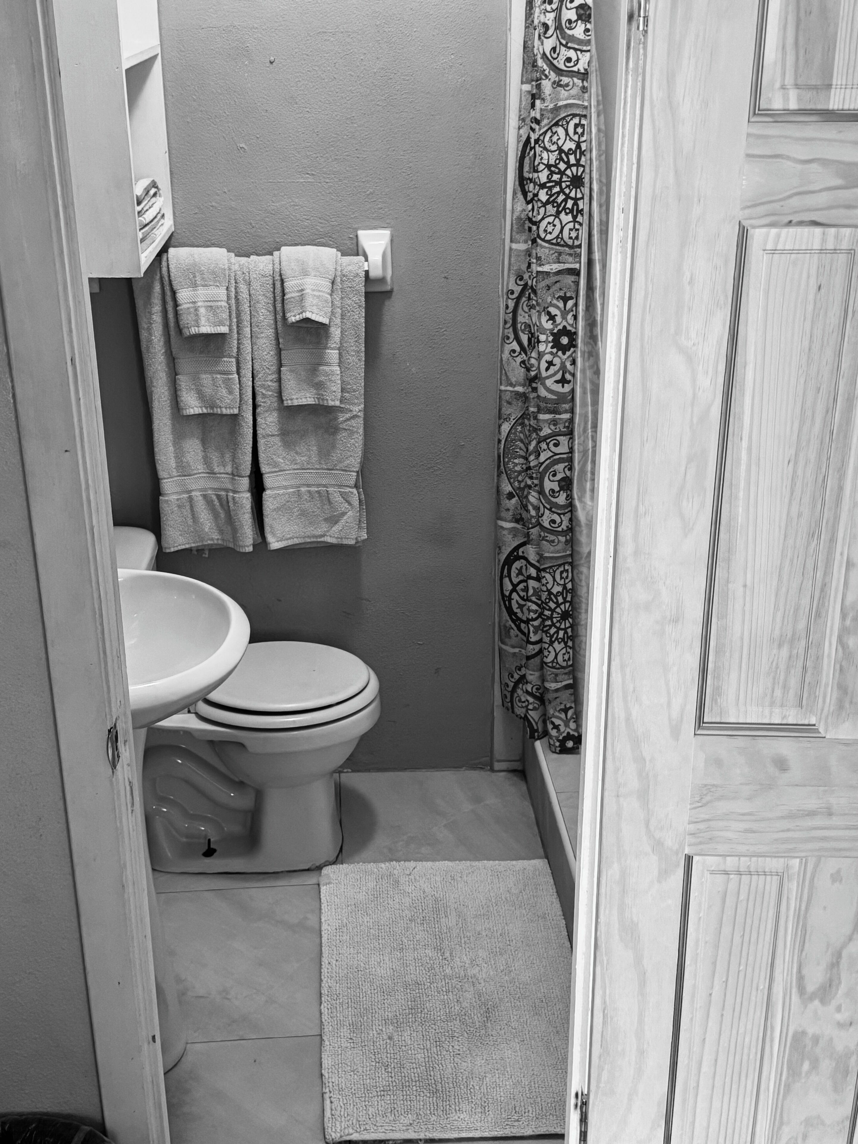 Een kleine, functionele badkamer met toilet, wastafel en douchegordijn.
