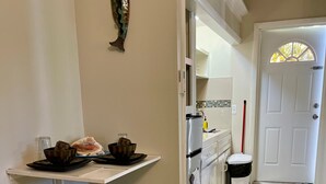 Une cuisine compacte avec un coin repas, une porte blanche et un petit tabouret.