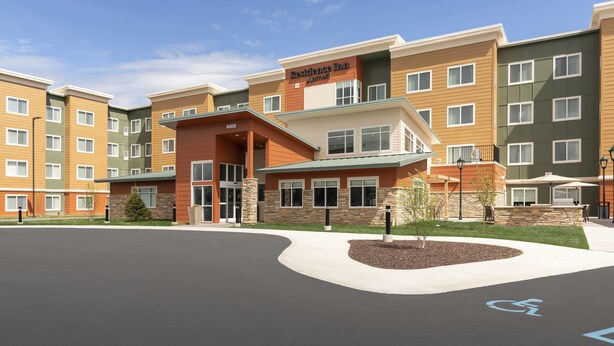 A multi-story hotel with a central entrance, a wheelchair-accessible ramp, and a landscaped area with small trees. - Residence Inn by Marriott Lafayette (Lafayette)