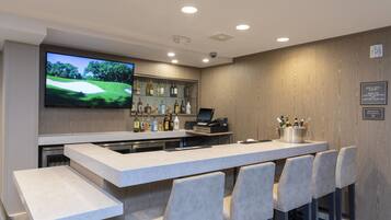 A bar area with a flat-screen TV, bar counter, and seating.