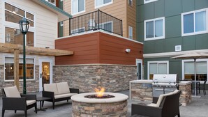 An outdoor patio with a stone fire pit, seating, and a grill. - Residence Inn by Marriott Lafayette (Lafayette)