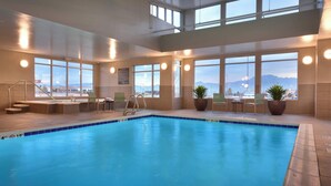 Una piscina interior con vistas a montañas a través de amplios ventanales.
