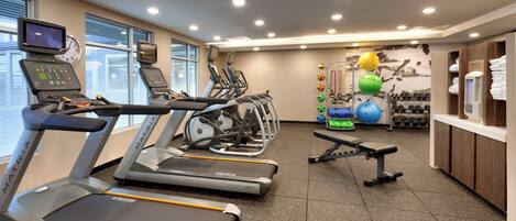 Un gimnasio con cintas de correr, pelotas de ejercicio y pesas.