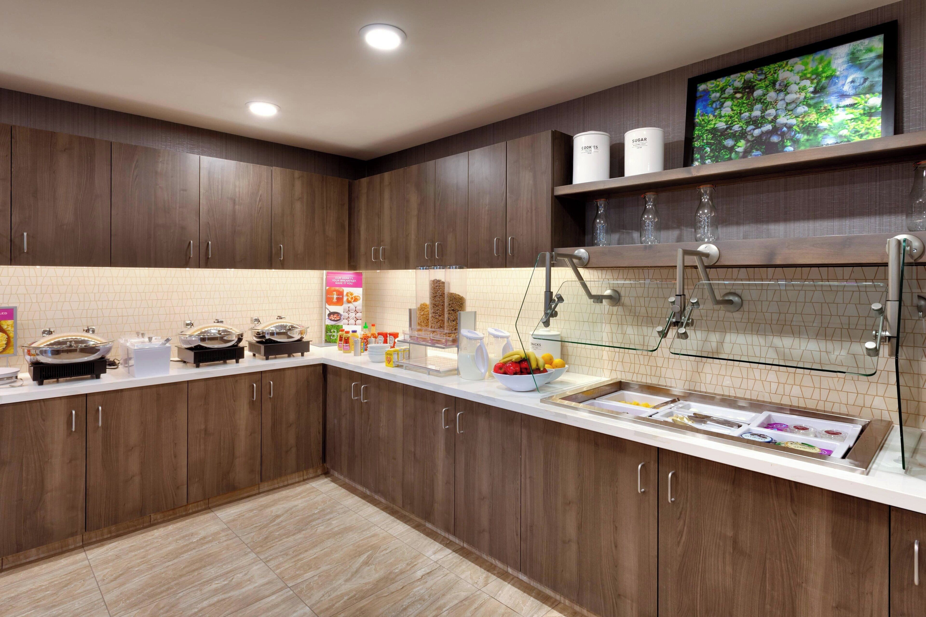 A modern kitchen with wooden cabinets, a white countertop, and a built-in sink.