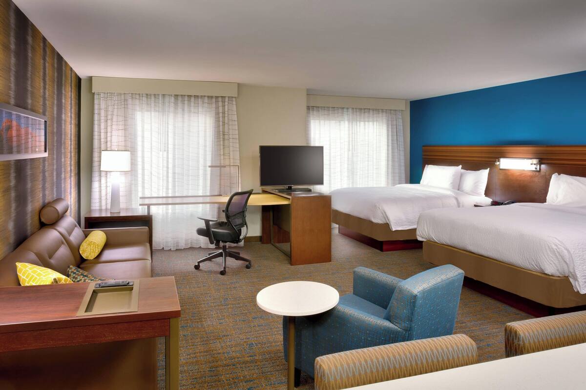 Une chambre d’hôtel avec un lit, un bureau, une chaise, une petite table et un téléviseur.