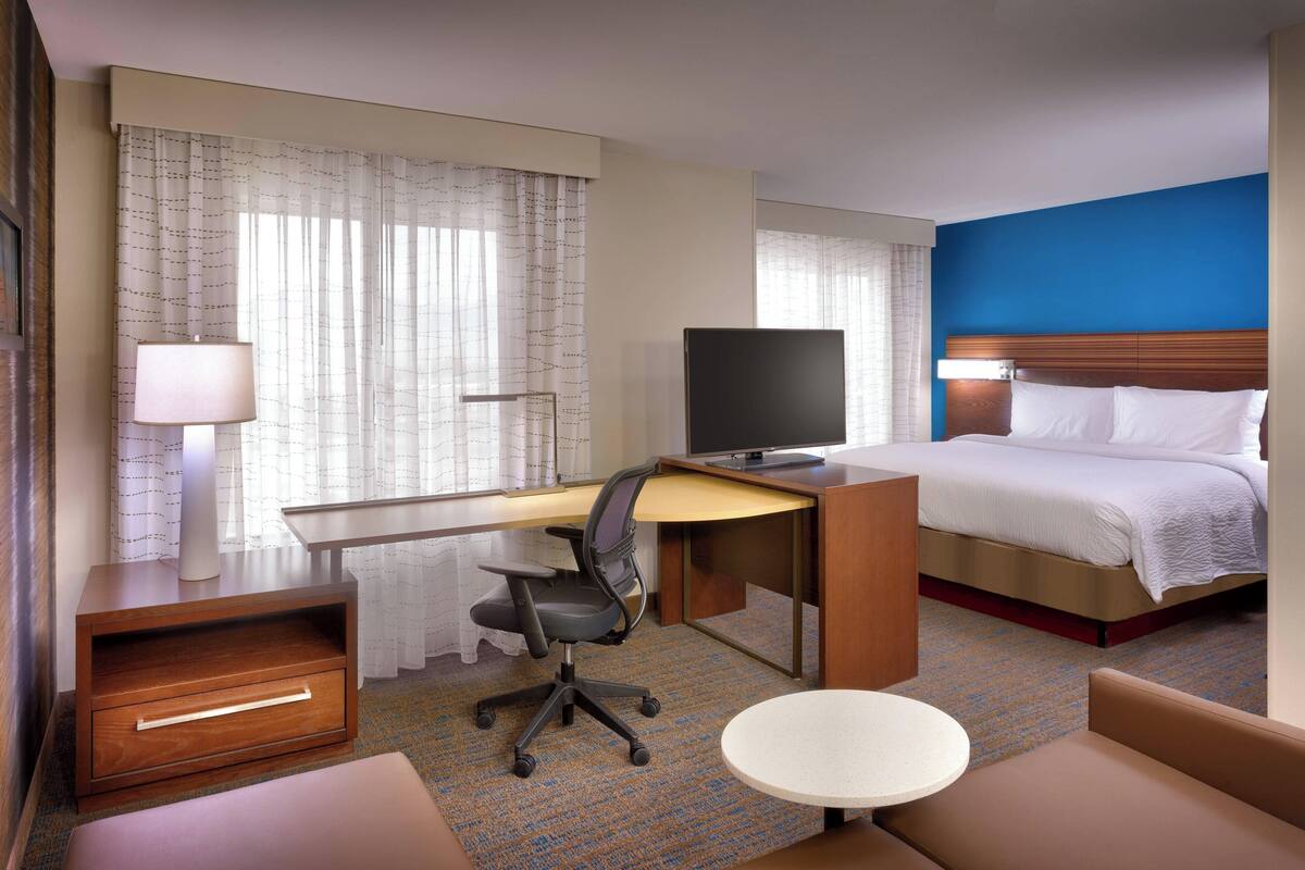Une chambre d’hôtel comprenant un lit, un bureau, une chaise, une télévision et une petite table.