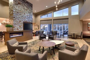 Relax in the inviting lobby with a fireplace, comfortable seating, and a large window offering a view of the outside.