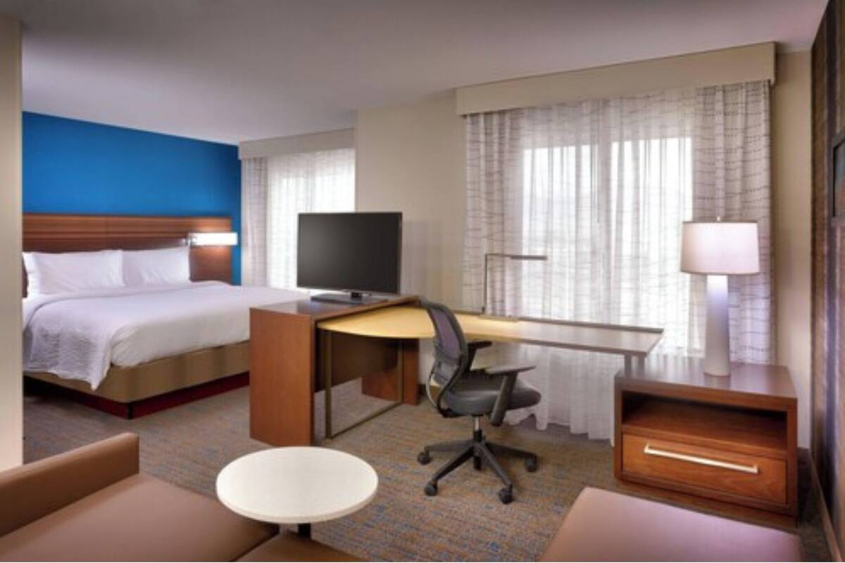 Une chambre d’hôtel équipée d’un lit, d’un bureau, d’une chaise, d’une lampe et d’un téléviseur.