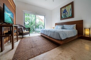 A bedroom with a bed, a desk, a chair, a TV, and a view of palm trees. - Turquesa by NAS (Playa del Carmen)