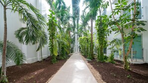 A corridor lined with tall trees and a tiled floor. - Turquesa by NAS (Playa del Carmen)