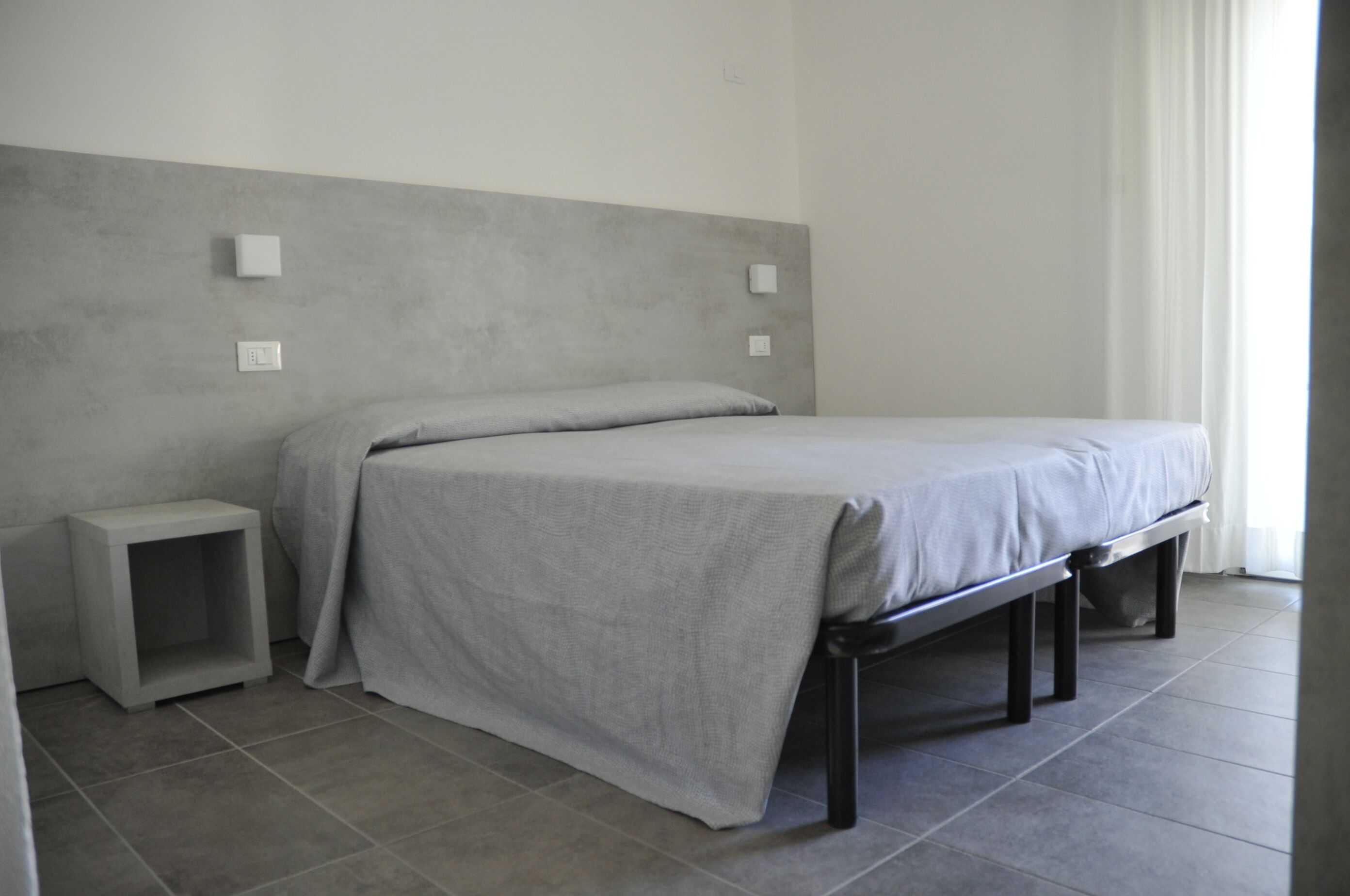 Un dormitorio minimalista con cama, mesitas de noche y una pared lisa.