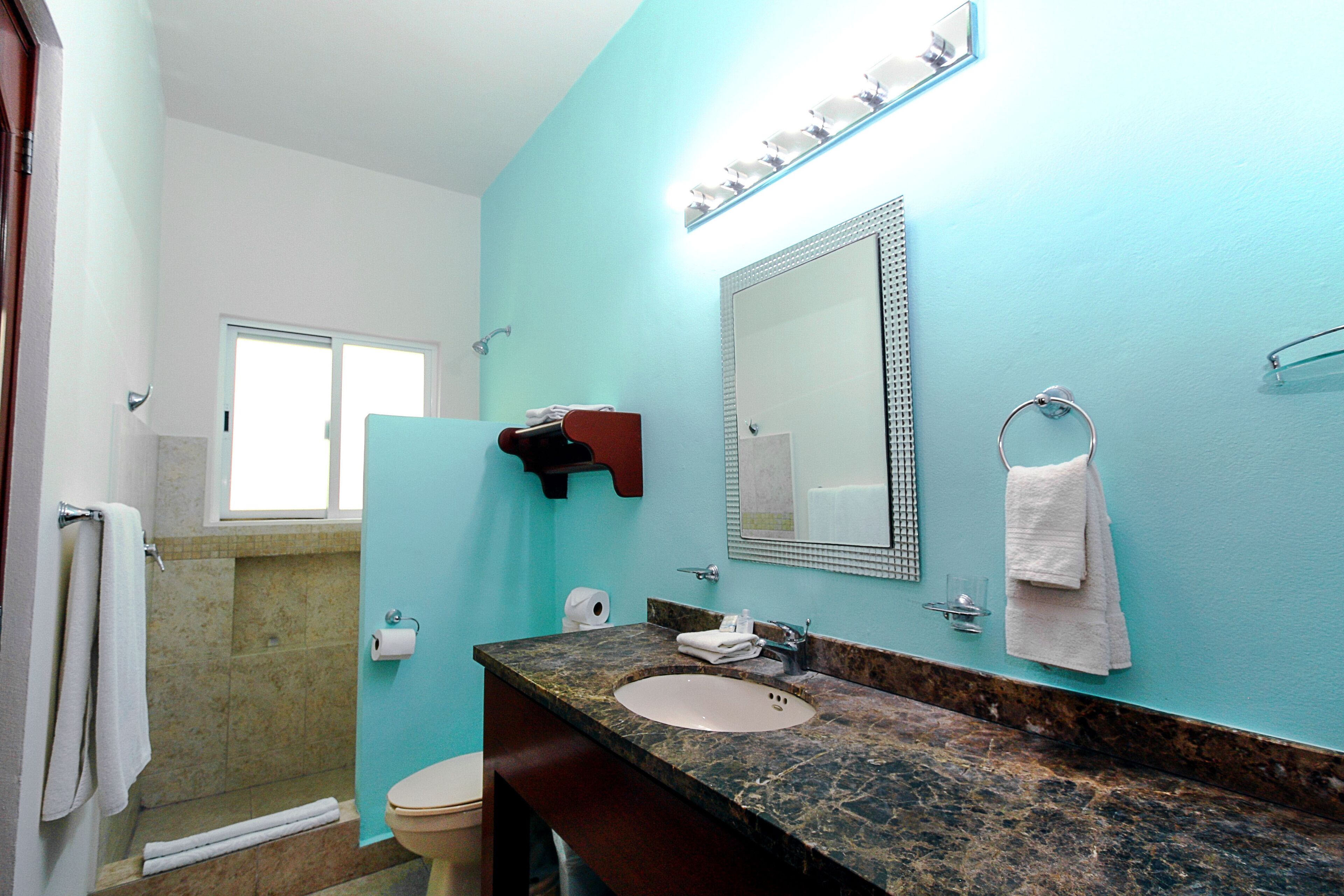 Une salle de bain avec un lavabo en marbre, un grand miroir et un porte-serviettes.