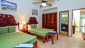 A hotel room with two beds, a ceiling fan, wooden furniture, and a bathroom with a mirror and sink. - Vista del Mar by NAS (Playa del Carmen)