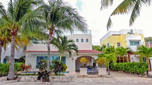 A resort with a pool area, palm trees, and a two-story building with a red-tiled roof. - Vista del Mar by NAS (Playa del Carmen)