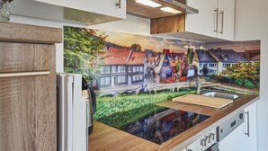 Eine Küche mit einer großen Wandmalerei eines europäischen Dorfes, modernen Geräten und einer Holz Arbeitsplatte.
