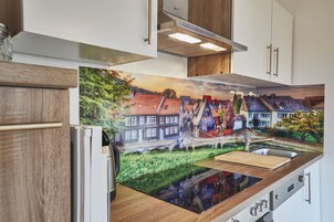 Una cocina con un gran mural de un pueblo europeo, electrodomésticos modernos y encimera de madera.