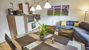 Ein modernes Wohnzimmer mit einem Glastisch, einer Couch und einer Küchenzeile.