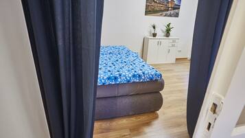 A bedroom with a bed, wooden flooring, a white cabinet, and a wall-mounted picture.