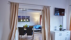Ein modernes Wohnzimmer mit Essbereich, einer Couch, einem Fernseher und einem Schrank.