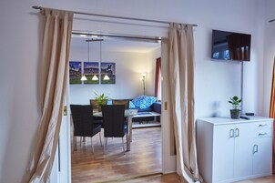 Una sala de estar moderna con comedor, sofá, televisor y mueble de almacenamiento.