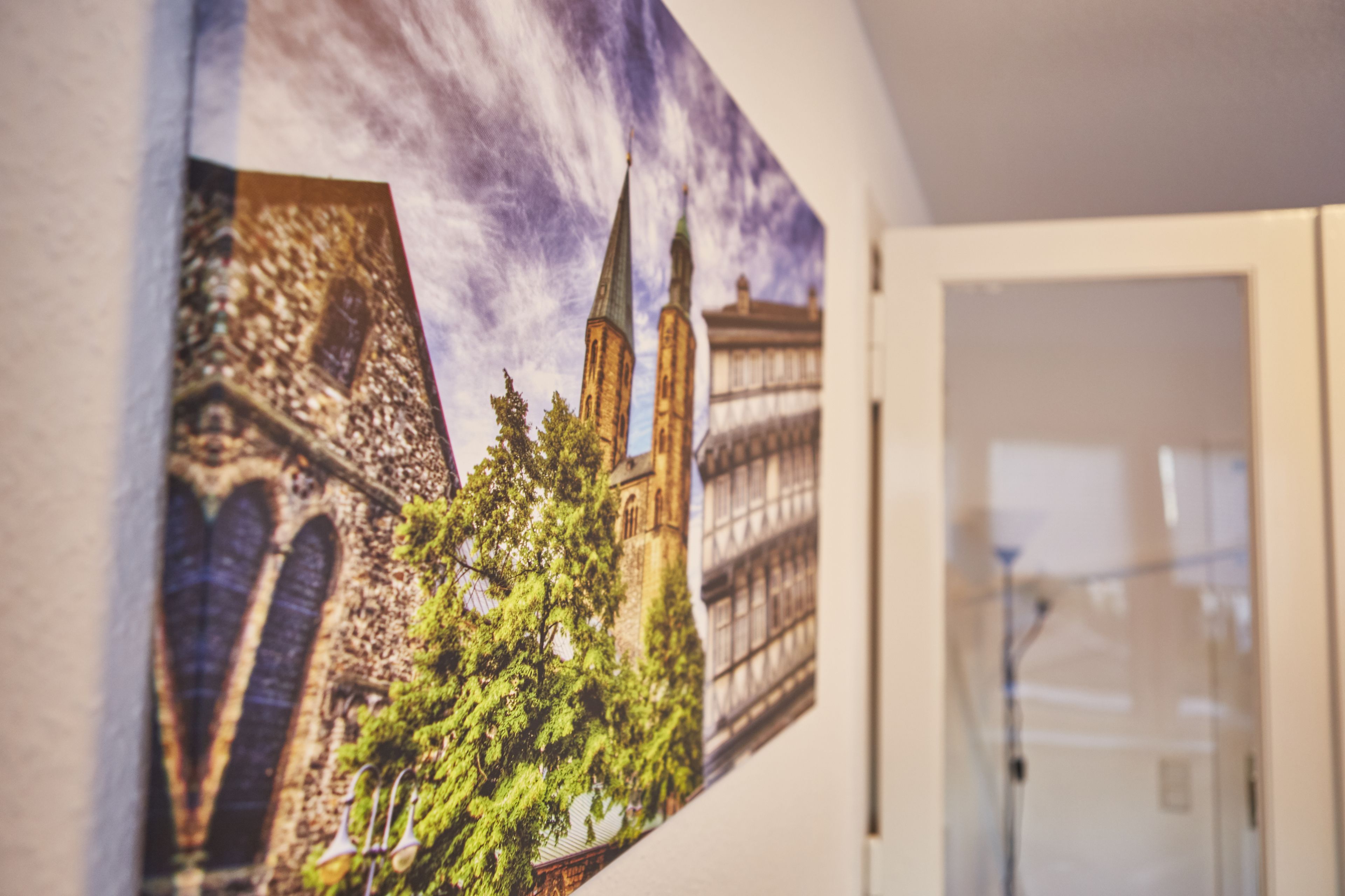 A framed artwork of a building with towers and trees.
