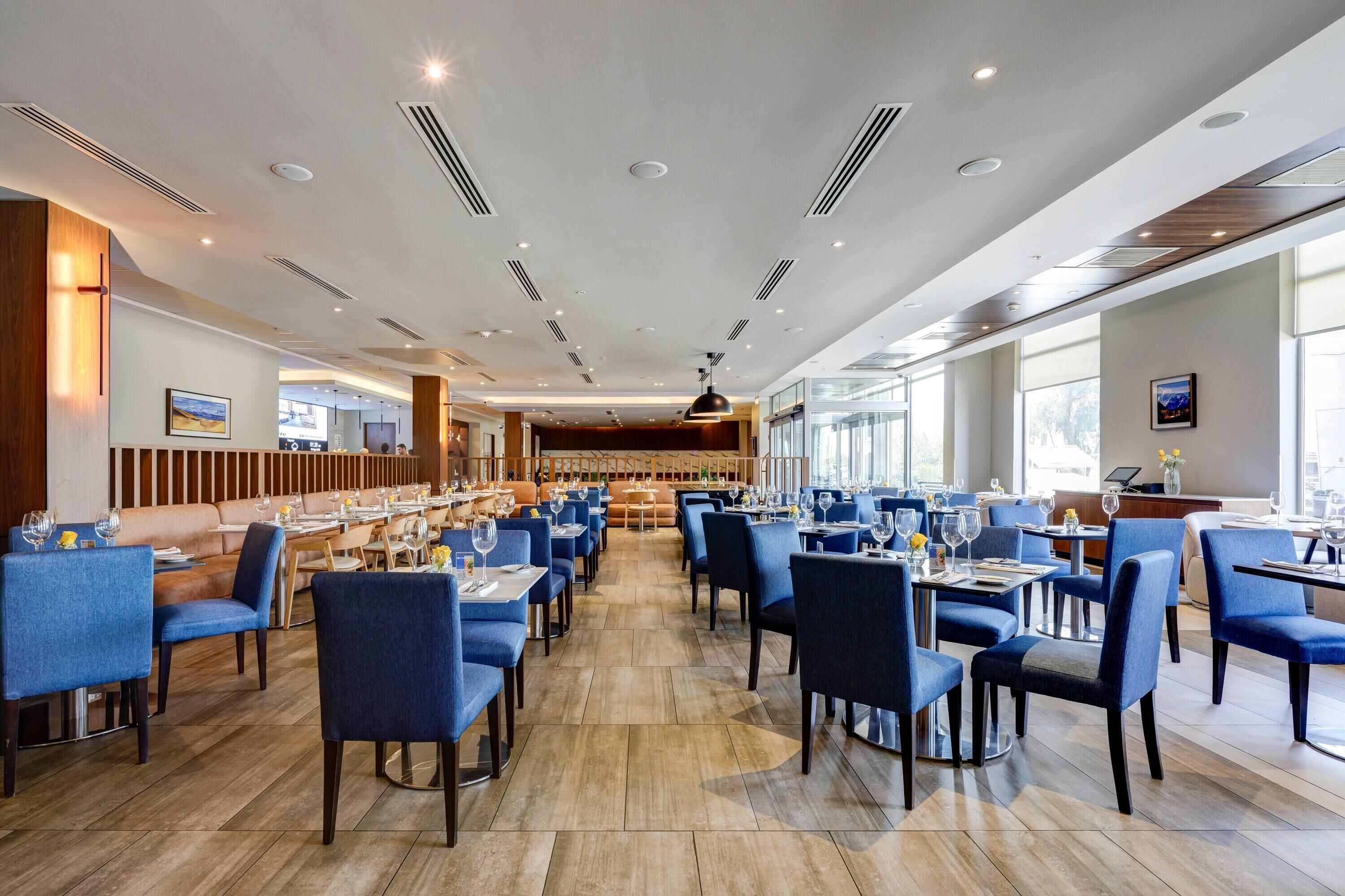 Un restaurante espacioso con techos altos, iluminación empotrada y una mezcla de asientos azules y marrones.
