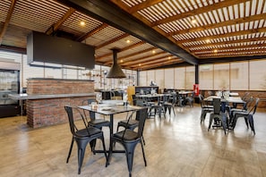 Un restaurante espacioso con detalles en ladrillo, vigas de madera y mobiliario moderno.