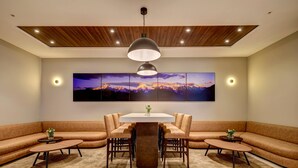 A modern dining area with a central table surrounded by chairs, a sofa, and two side tables. - Wyndham Santiago Aeropuerto (Santiago)