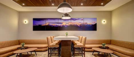 A modern dining area with a central table surrounded by chairs, a sofa, and two side tables.