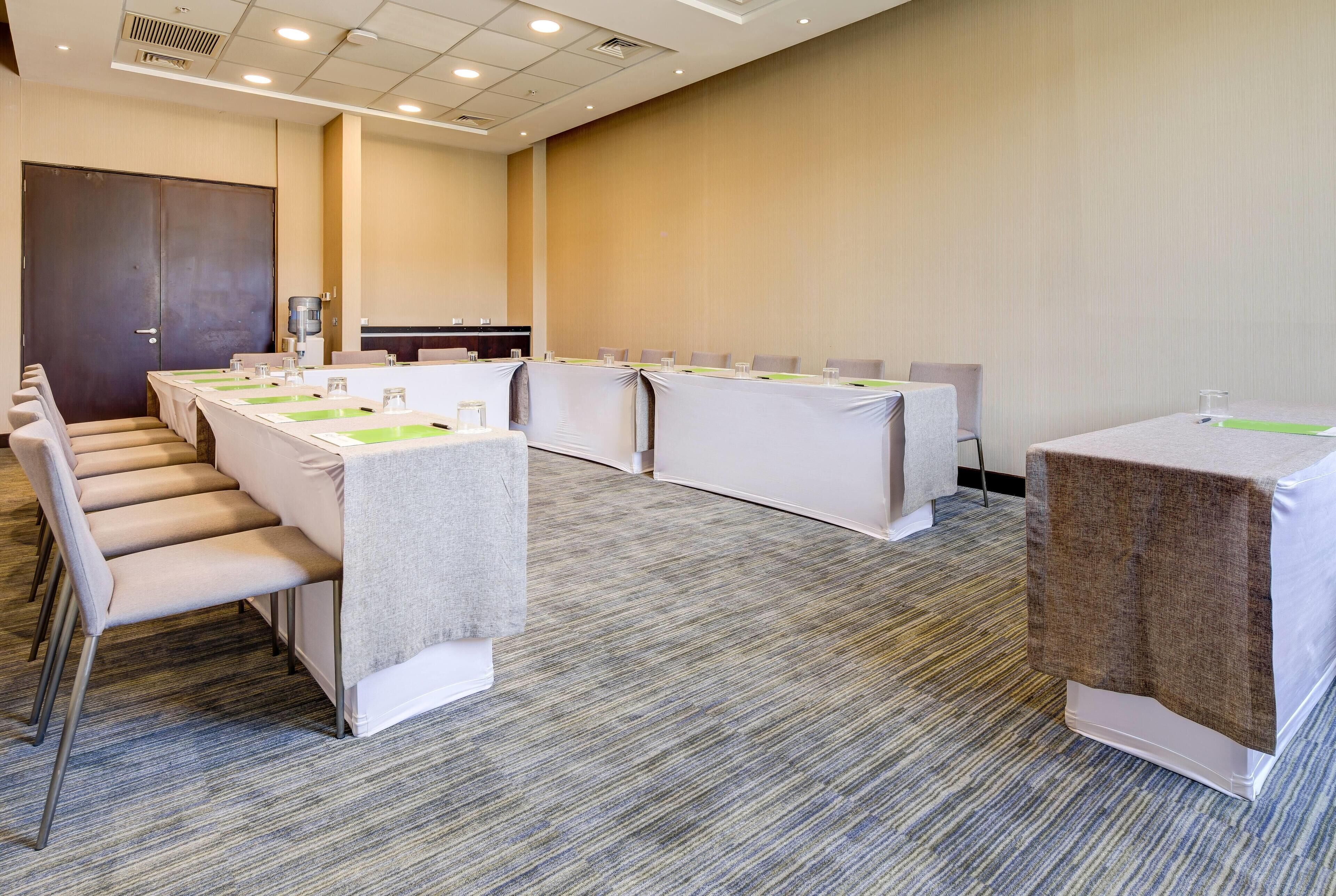 A conference room with long tables, chairs, and a carpeted floor.