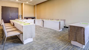 Une salle de conférence avec de longues tables, des chaises et un sol recouvert de moquette.