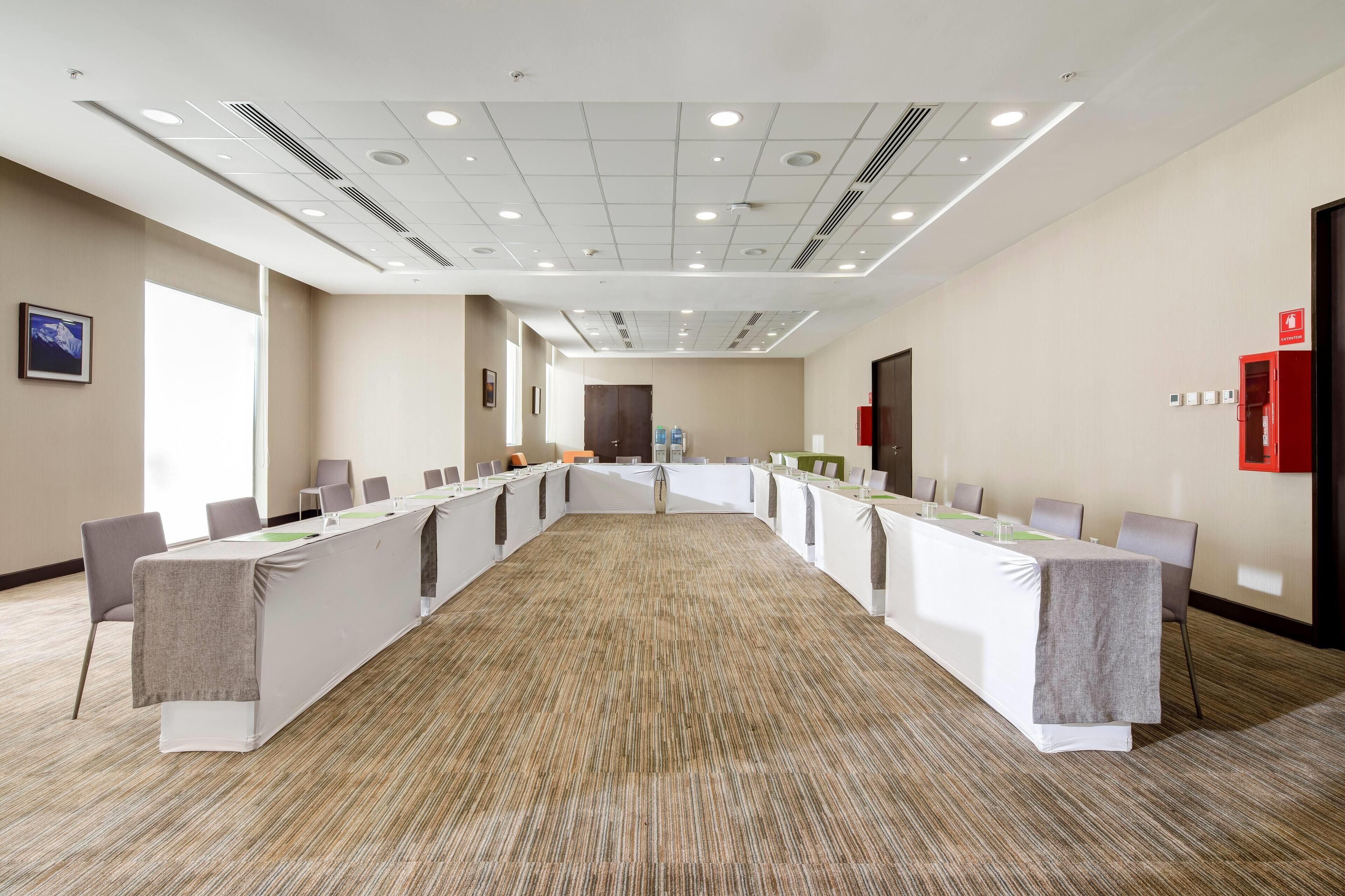 A conference room with a long table, chairs, and a carpeted floor.
