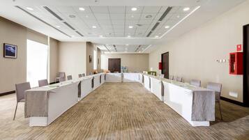 A conference room with a long table, chairs, and a carpeted floor.