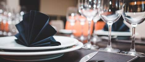 A table set with plates, cutlery, and wine glasses, indicating a formal dining arrangement.