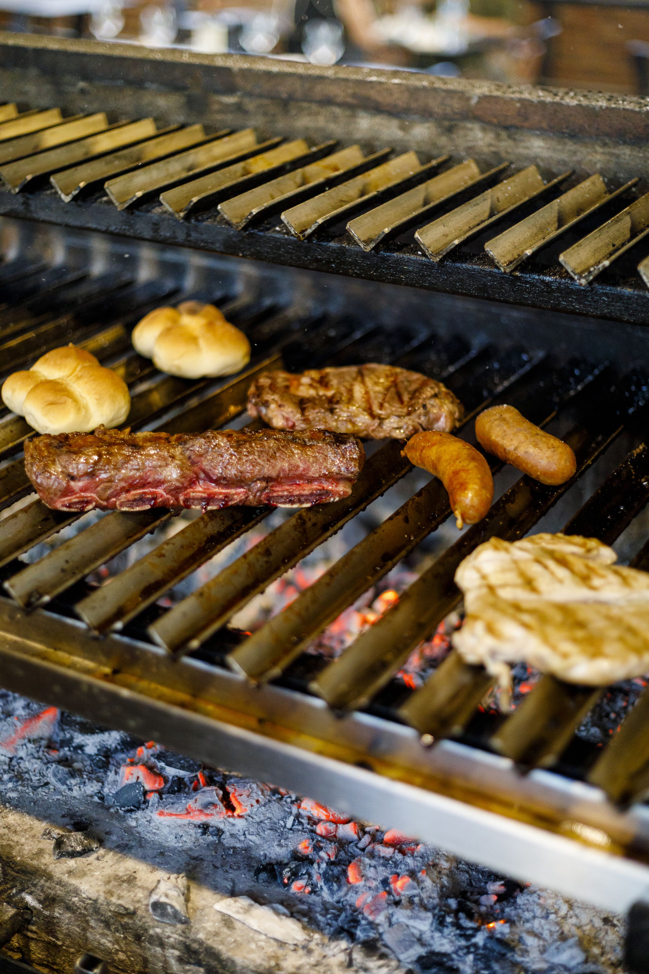 Een barbecue met verschillende vleessoorten en worstjes die worden gebakken.