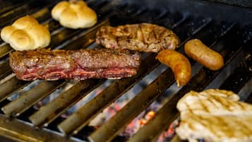 Een barbecue met verschillende vleessoorten en worstjes die worden gebakken.