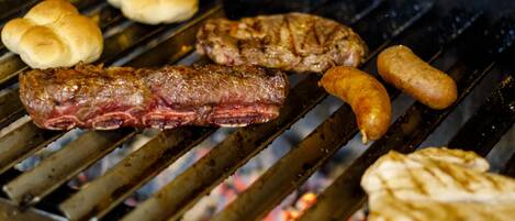 Una parrilla con diversos tipos de carne y salchichas asándose.