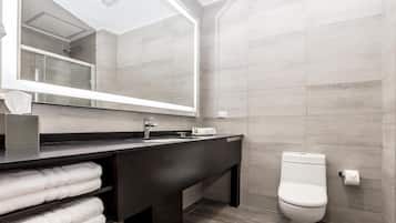Une salle de bain moderne avec un meuble-lavabo foncé, un grand miroir et des toilettes.