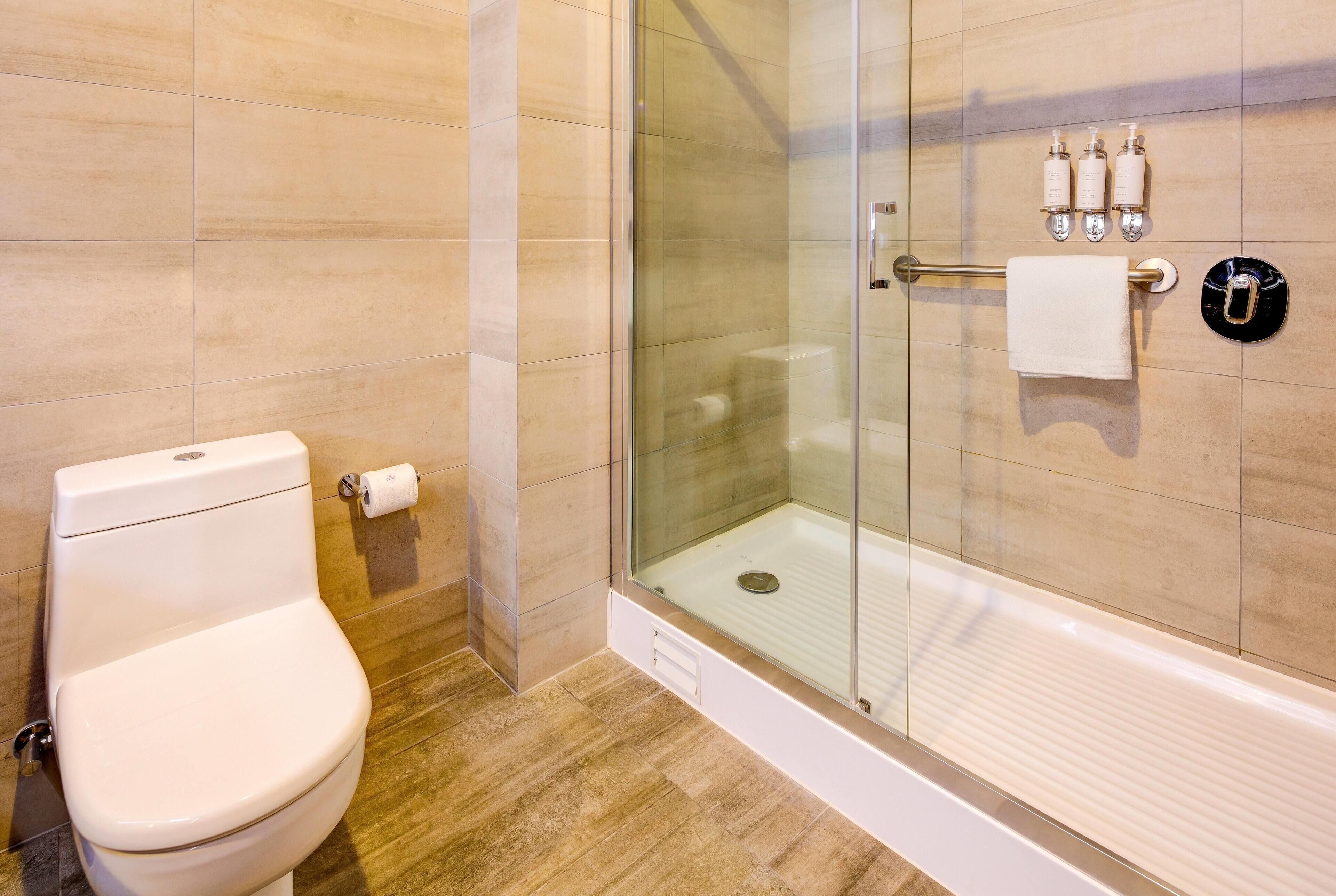 Een moderne badkamer met toilet, douchecabine van glas en toiletartikelen aan de muur.