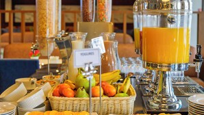 A buffet with various fruits, a juice dispenser, and breakfast items. - Wyndham Santiago Aeropuerto (Santiago)