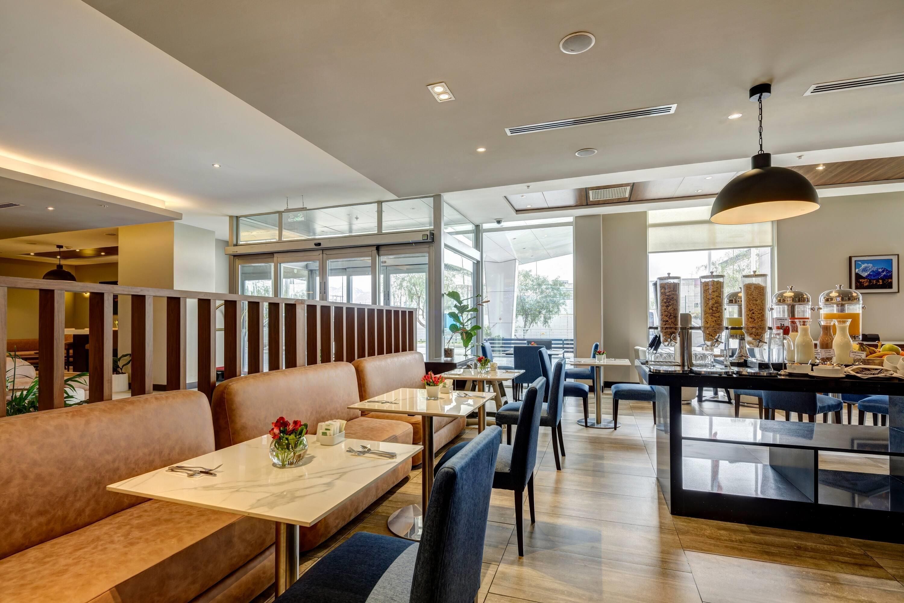 A modern restaurant with high ceilings, large windows, and a mix of seating options including booths and tables.