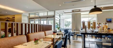 A modern restaurant with high ceilings, large windows, and a mix of seating options including booths and tables.