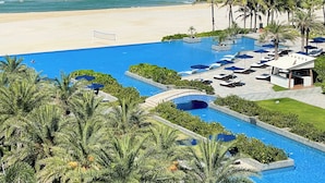 Un resort con piscina, palmeras y vista al mar.