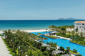 A resort with a large pool, palm trees, and a beach view. - Sheraton Grand Danang Beach Resort & Spa (Da Nang)