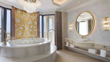 Un baño lujoso con una bañera independiente, un espejo grande y una encimera de mármol.