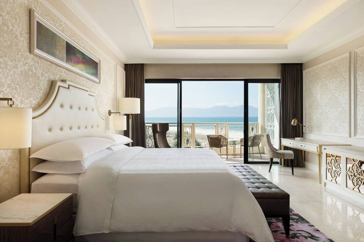A hotel room with a large bed, a desk, and a view of the ocean.