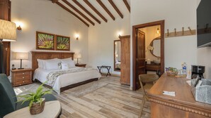 Een slaapkamer met een bed, nachtkastjes, een bureau, een stoel, een spiegel en een houten plafond.
