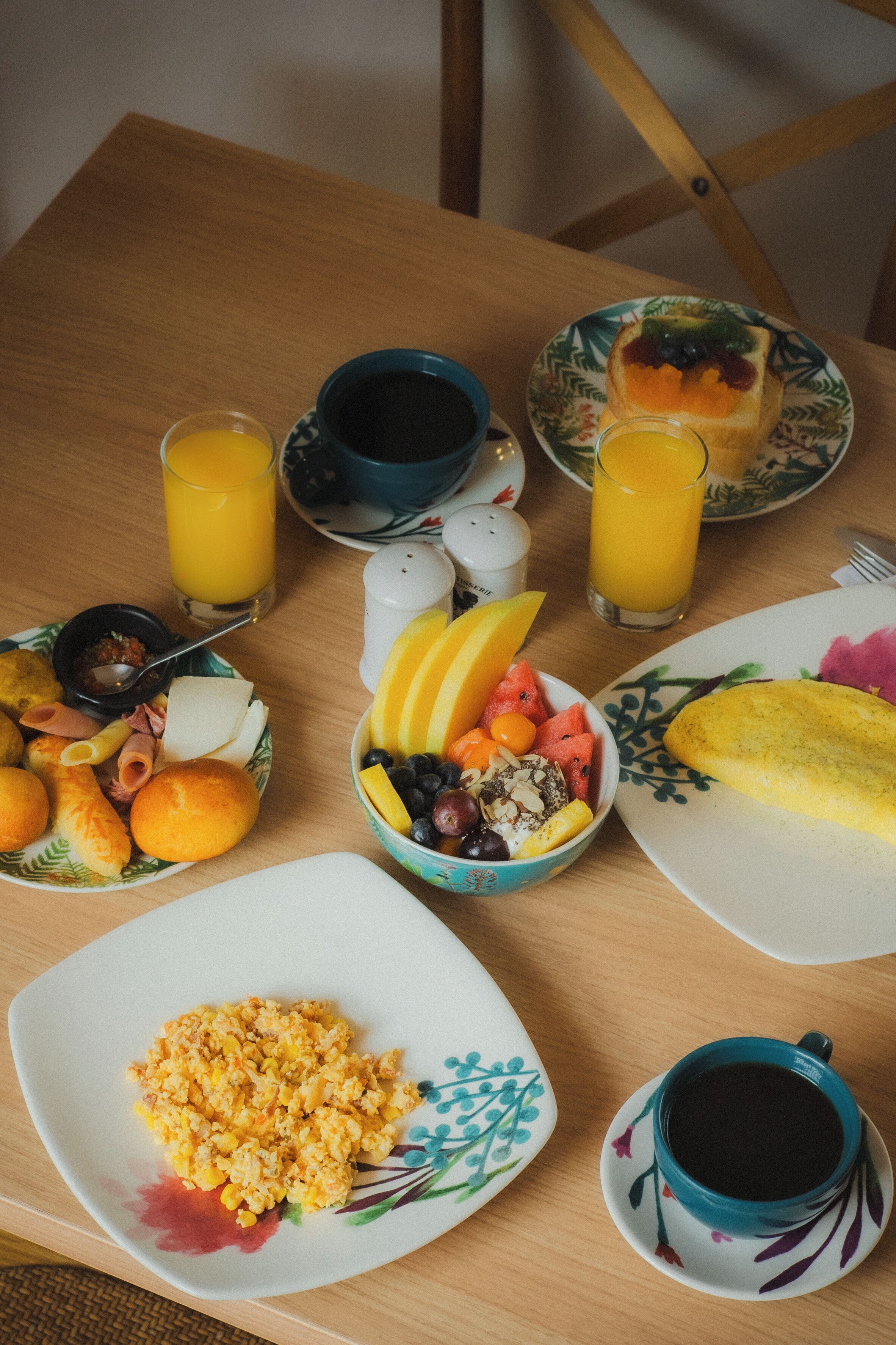 Een ontbijttafel met borden eten, glazen jus d'orange en een kop koffie.